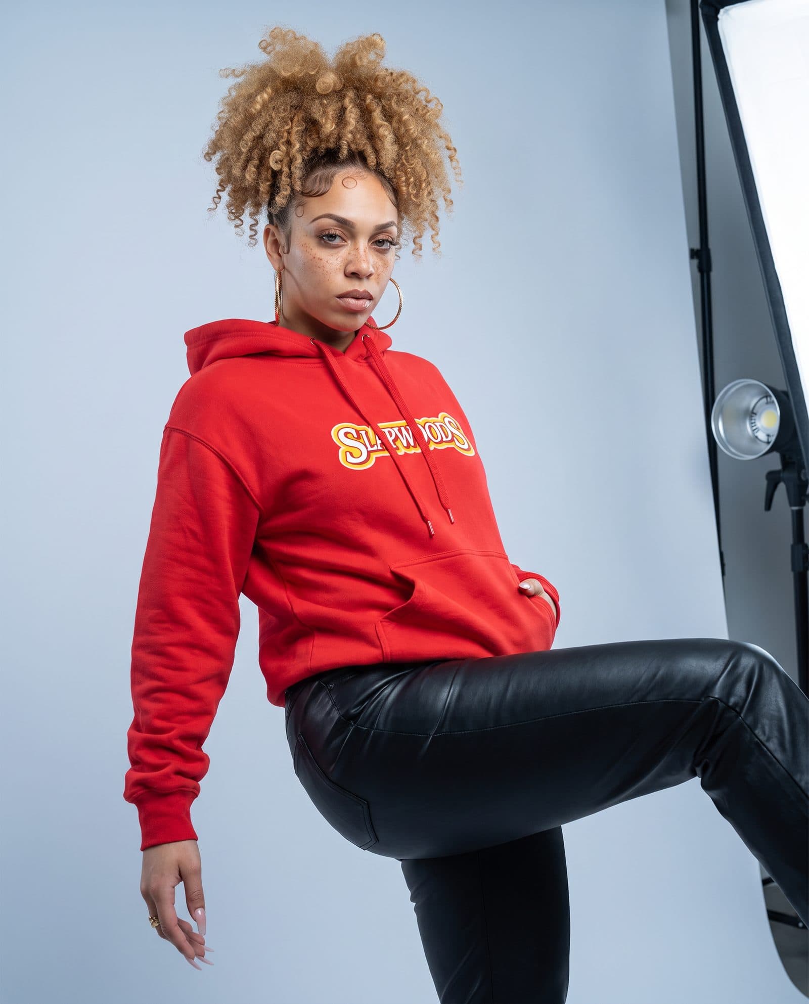 Model in the red Slapwoods hoodie and black leather pants